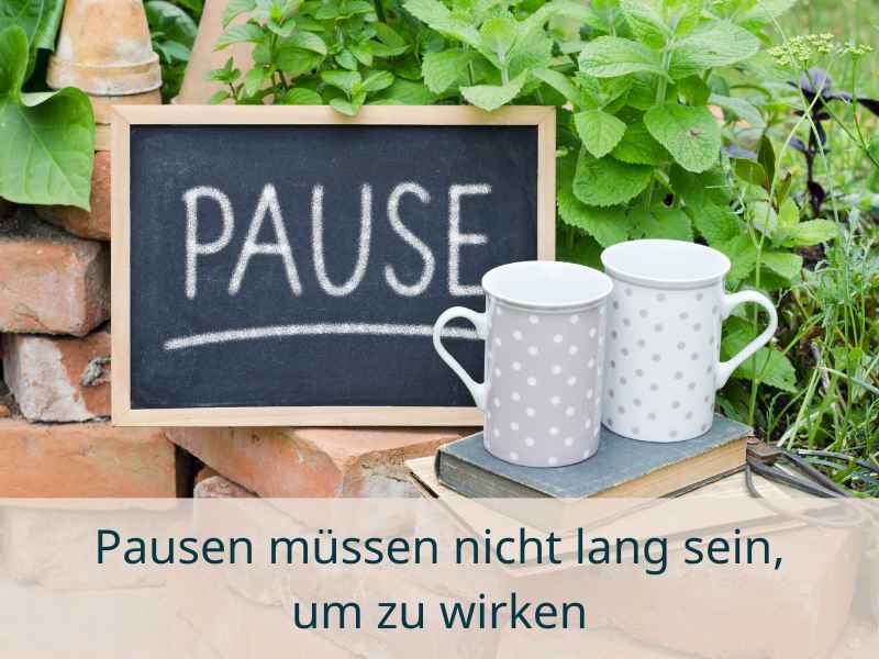 Tafel mit dem Wort "Pause" und zwei Tassen: Symbolbild für bewusste Mikro-Pausen im stressigen Alltag